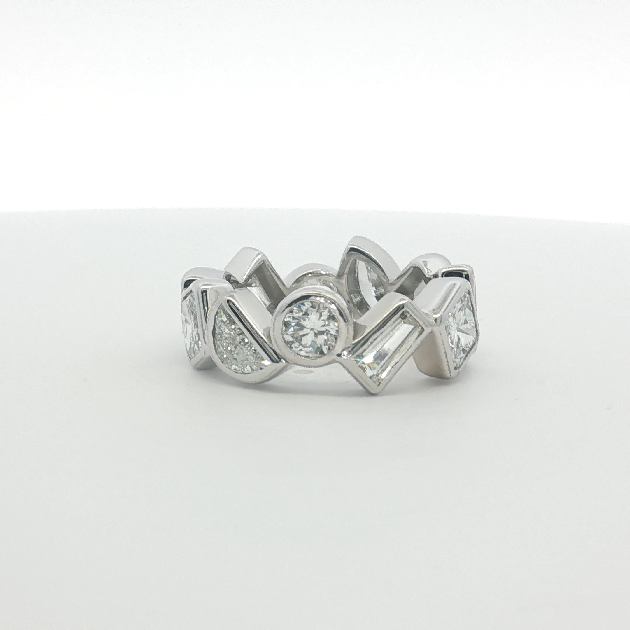 This exquisite 14k white gold eternity ring showcases a continuous band of multi-shaped diamonds, meticulously set to ensure maximum light reflection. Each diamond features exceptional clarity and a high-grade polish, creating a seamless stream of radiance. The timeless composition and symmetrical arrangement highlight the precision of the brilliant cutting style. Designed with a sleek profile, this piece serves as a sophisticated symbol of everlasting elegance, perfect for stacking or as a standalone statement.