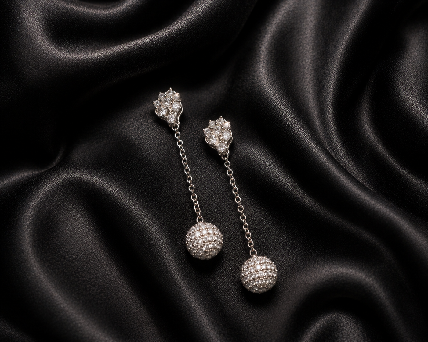 Luxury diamond drop earrings resting on black satin