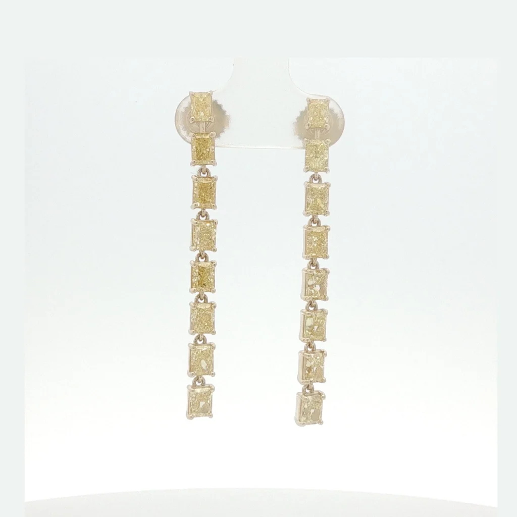 A continuous line of fancy intense yellow diamonds creates a striking silhouette in these linear dangle earrings. Each stone is articulated to allow graceful movement, securely set in a white gold framework.
